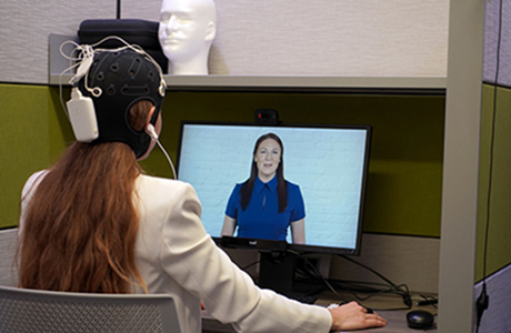 student sitting in front of computer while wearing monitoring device on her head