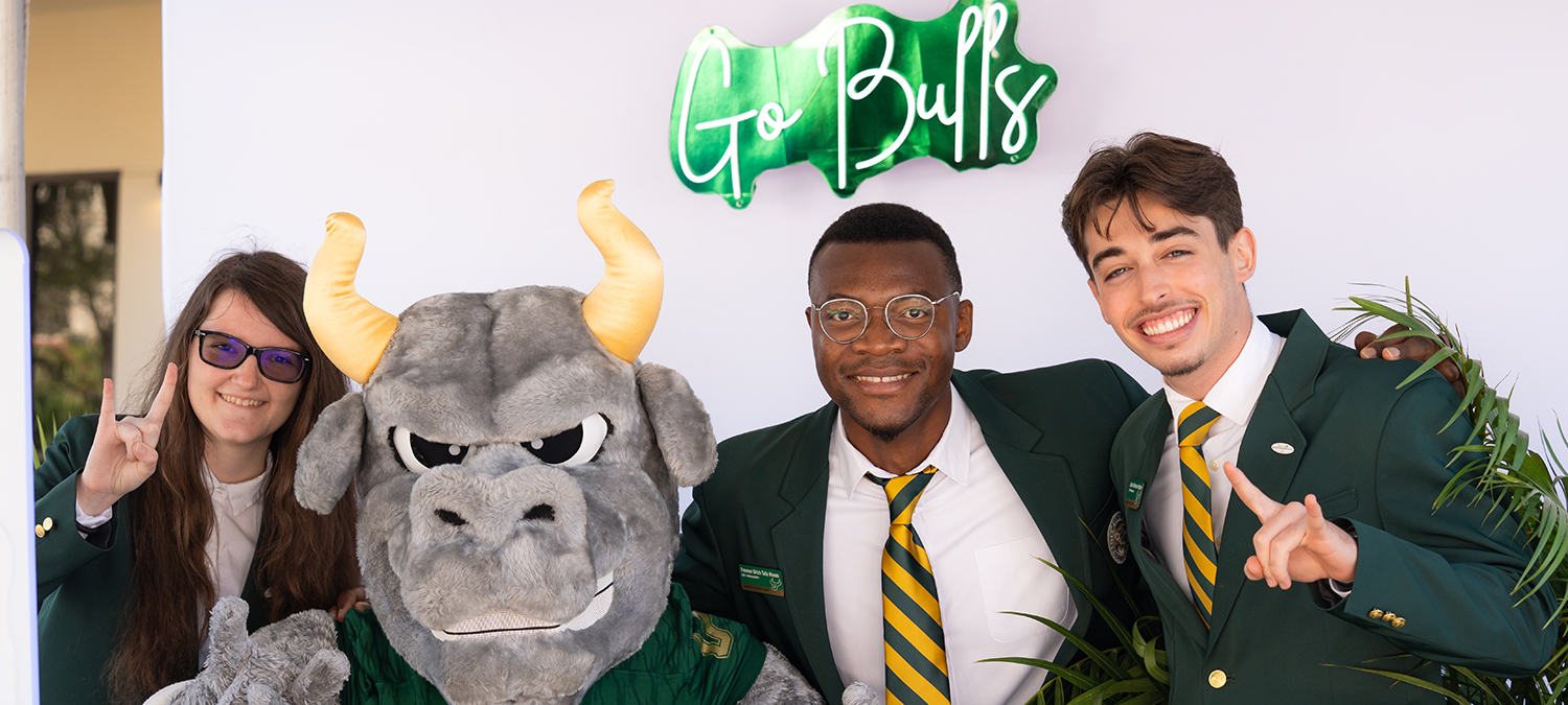 USF students display Horns Up sign and hold sign thanking donors at Sarasota-Manatee campus's Brunch on the Bay